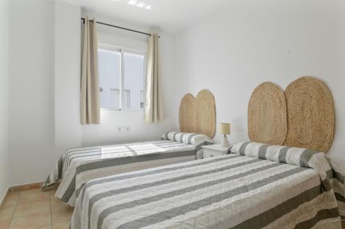 two beds in a room with white walls and a window at Apartamento Perez Zara 7 in Conil de la Frontera