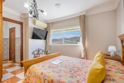 a bedroom with a bed and a tv and a window at Casa Carmen in Almuñécar