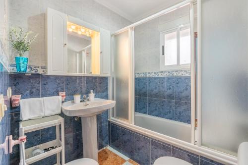 a blue tiled bathroom with a sink and a shower at Casa Carmen in Almuñécar