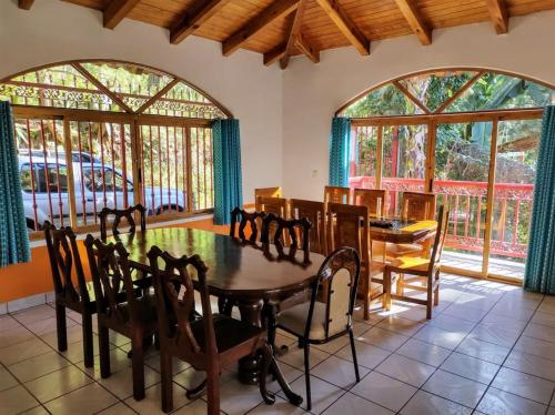 a dining room with a table and chairs and windows at Cabañas Monte Escondido in Mazamitla