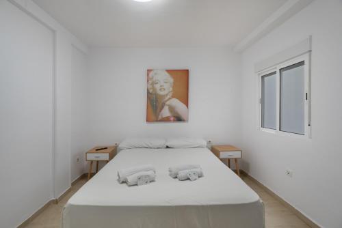 a white bedroom with a bed and a painting on the wall at Loft Guanapay 2 in Los Cristianos