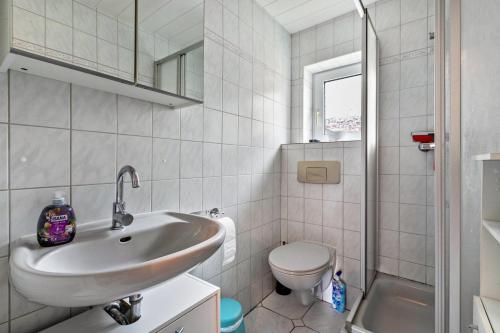 a white bathroom with a sink and a toilet at Bungalow vor Sylt in Klanxbüll