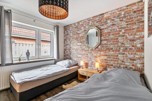 a bedroom with two beds and a brick wall at Bungalow vor Sylt in Klanxbüll
