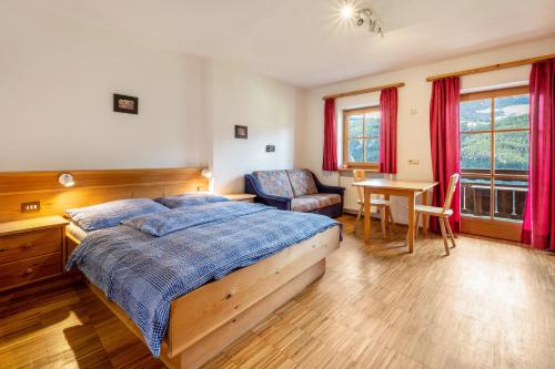 a bedroom with a bed and a chair and a table at Lindenhof Apt 2 in Vandoies