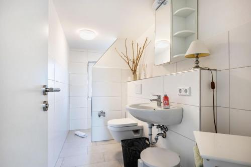 a white bathroom with a toilet and a sink at Huus achtern Diek in Nordstrand