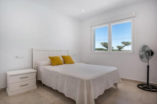 a bedroom with a bed with yellow pillows and a window at Casa Robert in Conil de la Frontera