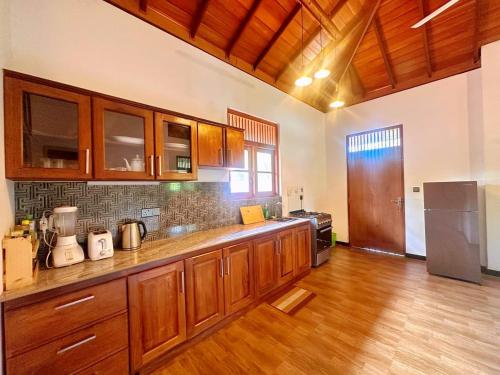 a kitchen with wooden cabinets and a wooden floor at Anu villa Bentota in Bentota