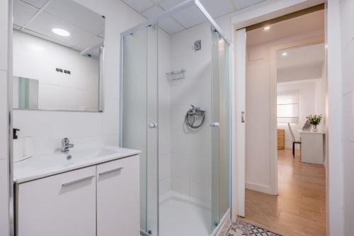 a white bathroom with a shower and a sink at Piso Garaje Gratis Granada in Granada