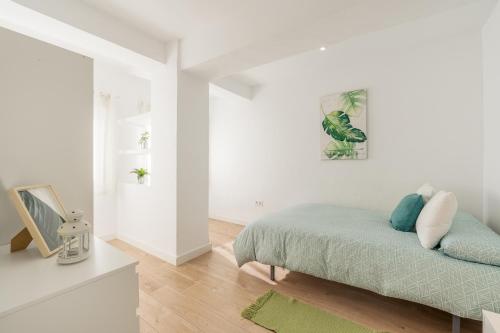 a white bedroom with a bed and a picture on the wall at Piso Garaje Gratis Granada in Granada