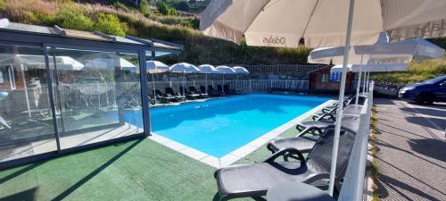 a swimming pool with chairs and an umbrella at Appartement Valmeinier 1800 in Valmeinier