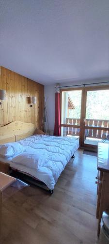 a large bed in a room with a large window at Appartement Valmeinier 1800 in Valmeinier
