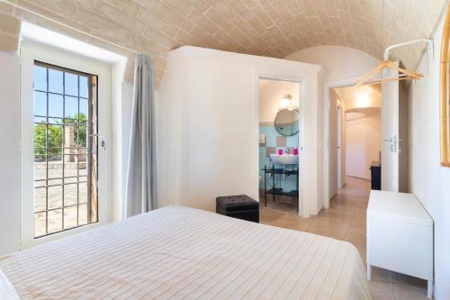 a bedroom with a white bed and a bathroom at Trulli i Cedri, Monopoli in Monopoli