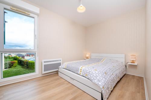 a white bedroom with a bed and a large window at L'Optimist, parking, proche plages in Arzon