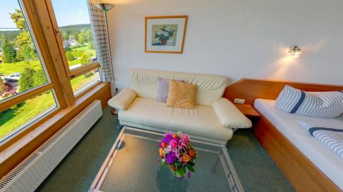 a living room with a couch and a table with flowers at Ferienhotel Mühlleithen in Klingenthal