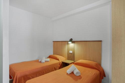 two beds in a hotel room with orange sheets at Estudio Yumbo Playa in San Bartolomé