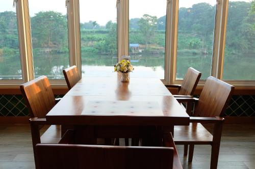 a dining room table with a vase of flowers on it at Princess River Kwai Hotel in Kanchanaburi