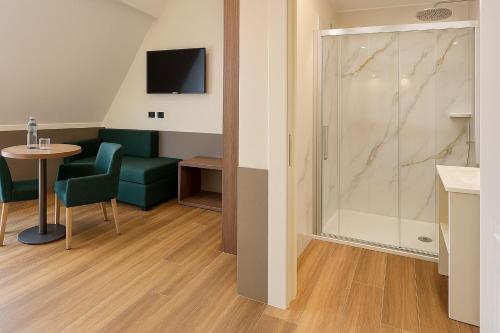 a room with a table and a glass shower at JR Hotels Bocconi Milano in Milan