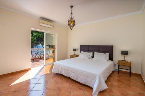 a bedroom with a white bed and a glass door at Poiso da Águia in Carvoeiro