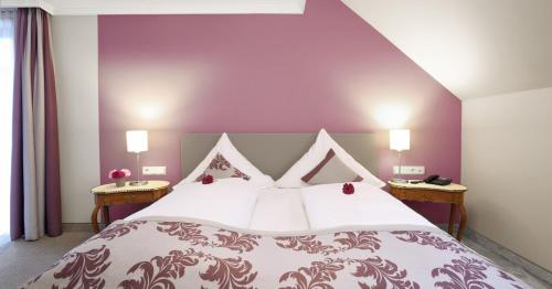 a bedroom with a large bed with a purple wall at Hotel Restaurant Paradeismühle in Klingenberg am Main