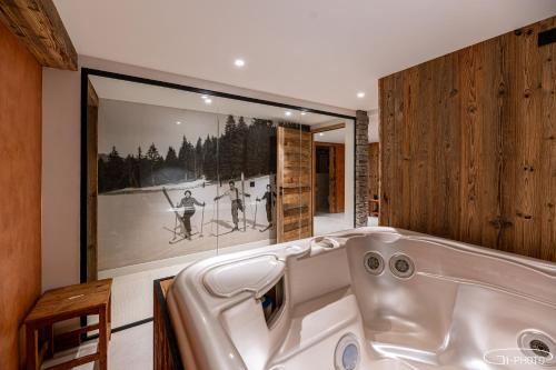 a bath tub in a room with a picture of skiers at Chalet Azureva Sauna, Jacuzzi, Spa in Levassaix