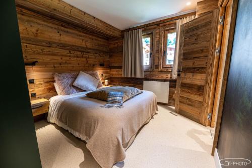 a bedroom with a bed and a wooden wall at Chalet Azureva Sauna, Jacuzzi, Spa in Levassaix