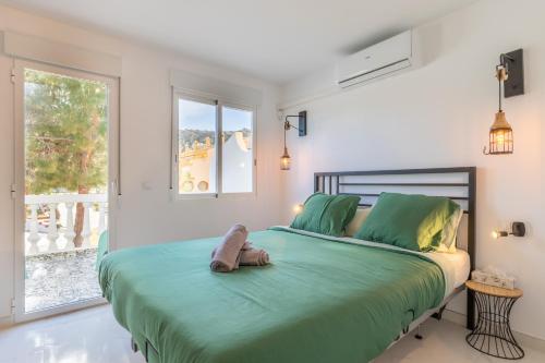 a bedroom with a bed with green sheets and a window at Sol y Sombra in El Campello