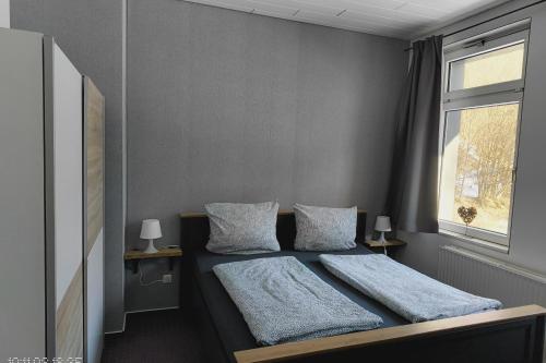 a bedroom with a bed with two pillows and a window at Fewo einzigartige Aussicht im Harz in Walkenried