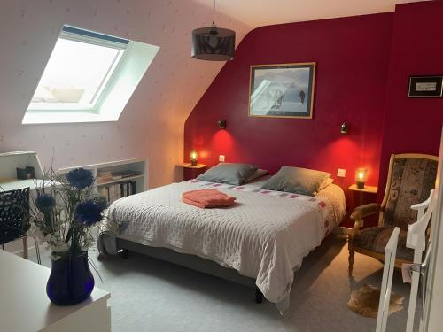 a bedroom with a red wall with a bed and a window at Chambre d'hôtes à Lesneven in Lesneven