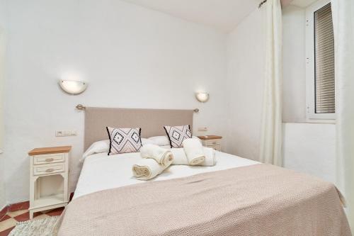 a white bedroom with a large bed with two pillows at Casa Victoria G in Nerja
