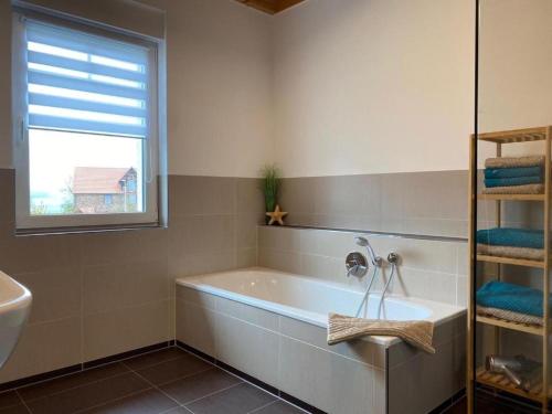 a bathroom with a tub and a window and a sink at Ferienhaus Marlen in Naumburg