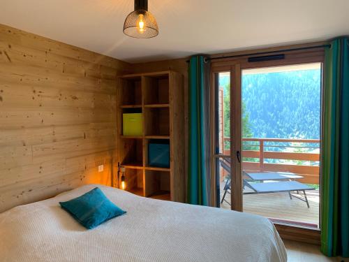 a bedroom with a bed and a balcony with a table at Flambeaux A 12 Roca immobilier in Châtel