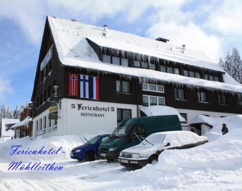 a building covered in snow with a car parked in front at Ferienhotel Mühlleithen in Klingenthal