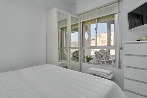 a white bedroom with a bed and a window at Great views studio A84 in Torrox