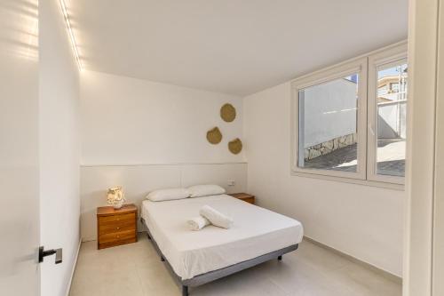 a white bedroom with a bed and a window at Apartamento L'escala - Bajos in L'Escala