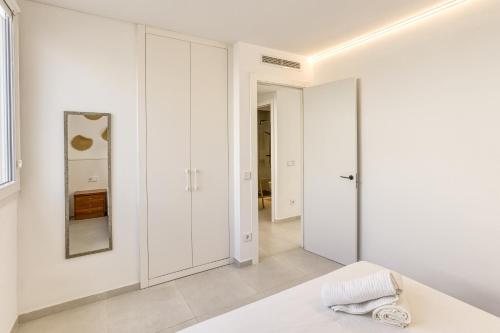 a white bedroom with white cabinets and a mirror at Apartamento L'escala - Bajos in L'Escala