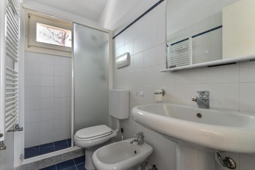 a white bathroom with a sink and a toilet at Appartamento La Spiga in Procchio