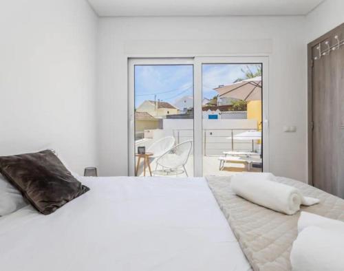 a white bedroom with a bed and a balcony at Casa da Madou in Setúbal