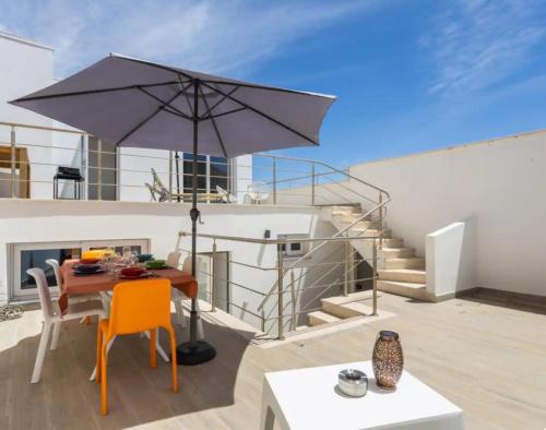 a patio with a table and an umbrella at Casa da Madou in Setúbal