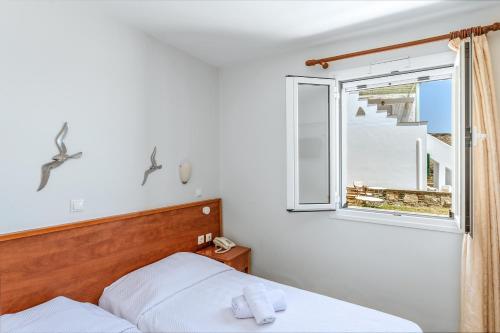a bedroom with a bed and a window at Anemologio 201 Tinos in Agios Ioannis