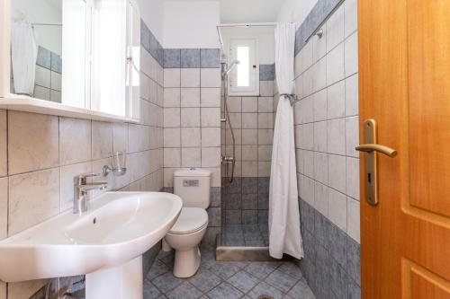 a bathroom with a white sink and a toilet at Anemologio 201 Tinos in Agios Ioannis
