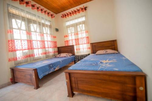 two beds in a room with two windows at Villa Ransanda in Warakagoda