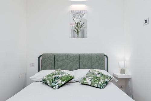 a bed with a green headboard and two pillows at Villa Cormorani 1 in Golfo Aranci