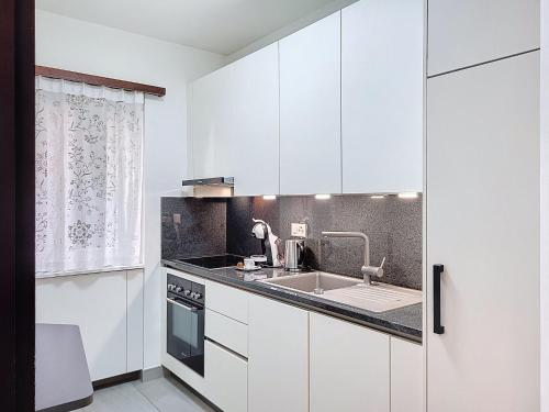 a kitchen with white cabinets and a sink at Apartment Superpanorama II by Interhome in Lugano