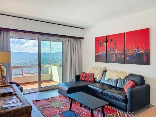 a living room with a black leather couch and a large window at Apartment Superpanorama II by Interhome in Lugano