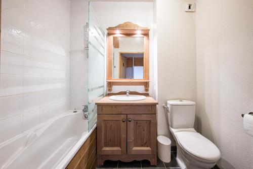 a bathroom with a sink and a toilet and a mirror at Duplex confortable avec piscine in La Toussuire