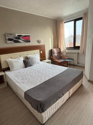 a bedroom with a large bed and a chair at Private Rooms Trakiets in Pomorie