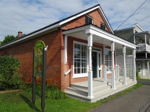 a red brick house with a white porch at villa du vignoble in Dunham