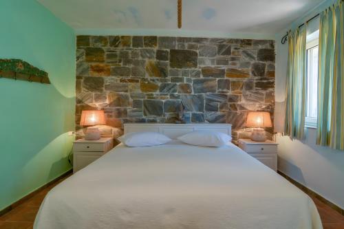 a bedroom with a large bed with a stone wall at Vitali River House Andros in Andros