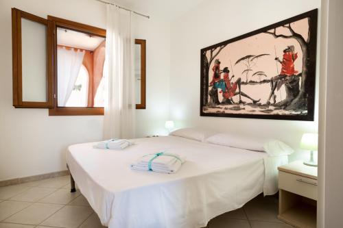 a bedroom with a bed with white sheets and a painting on the wall at Granito's in Monte Petrosu