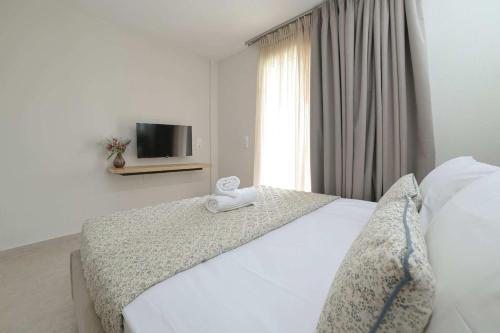 a bedroom with a large white bed with a tv on the wall at Sunset View House In Chalkidiki in Nea Potidaea